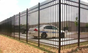 Commercial fence with police car parked nearby, providing secure perimeter protection for a commercial or government facility