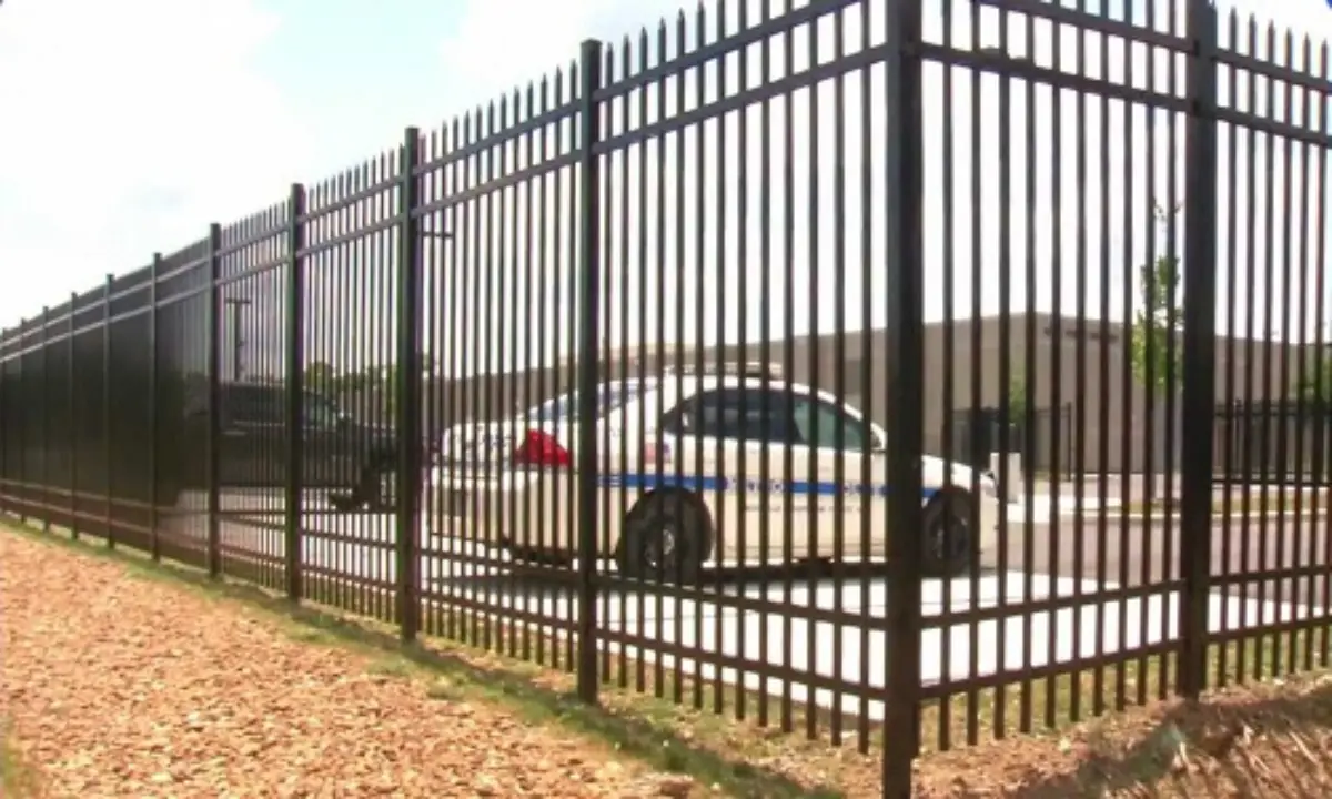 Commercial fence with police car parked nearby, providing secure perimeter protection for a commercial or government facility