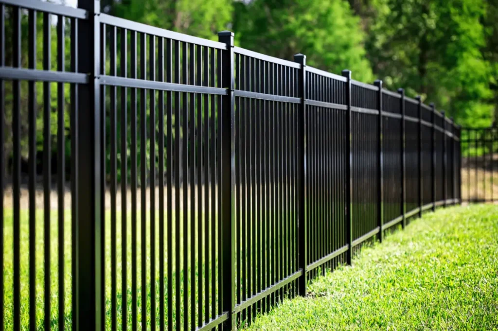 Fence contractor installing black metal fence for residential security and modern curb appeal