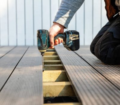 Custom decks construction with a worker using a drill to install a deck board